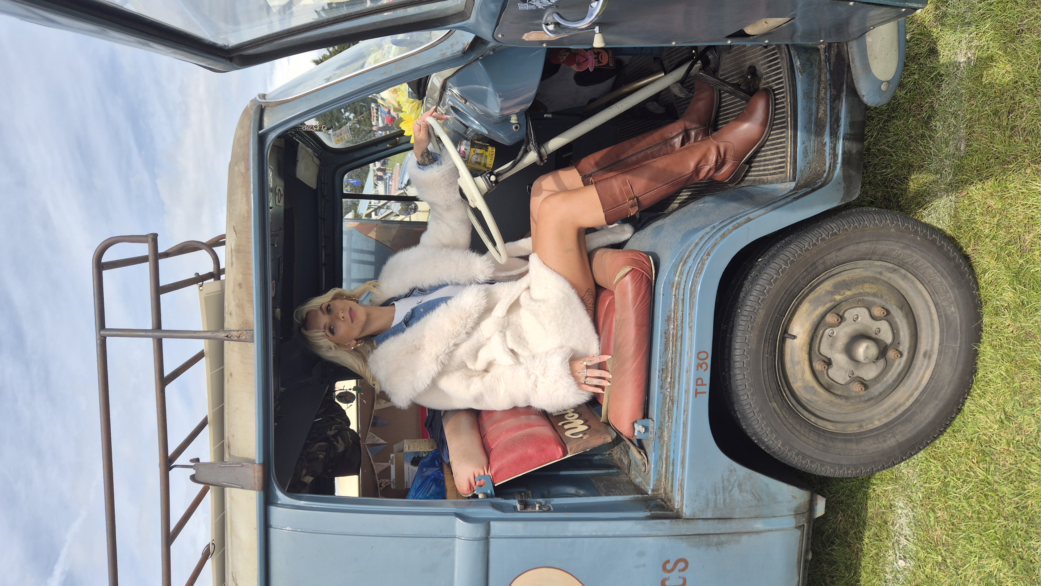 Emma Townsend in a faux-fur coat sitting in a vintage camper van